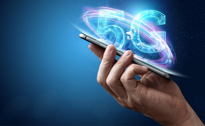 Eine Hand hält ein Smartphone mit einer leuchtenden "5G"-Grafik darüber, die fortschrittliche Mobilfunktechnologie und potenzielle Chancen für Aktienanleger symbolisiert.