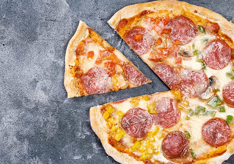 A pepperoni pizza with a slice separated on a gray, textured surface, similar to the fractional slices that allow you to enjoy only part of the whole.