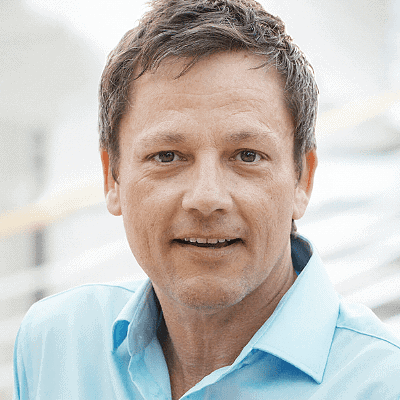 Carsten Berger with short brown hair and a light blue collared shirt, looking into the camera with a neutral expression - ideal for use in speaker profiles or when introducing speakers.