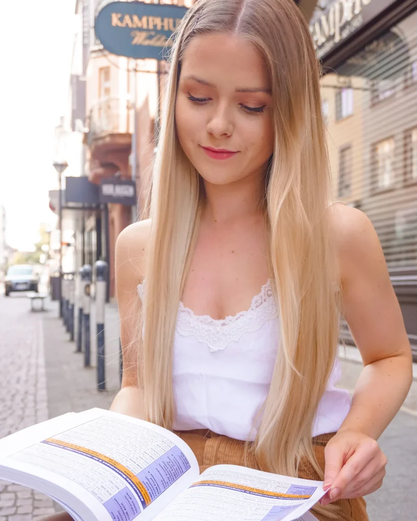 Eine Frau liest auf einer Stadtstraße ein Buch.