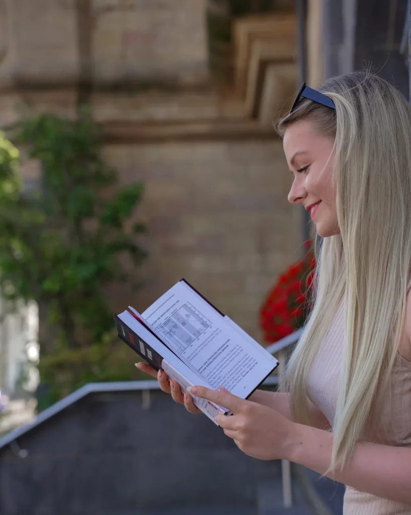 Eine Frau liest draußen ein Buch.