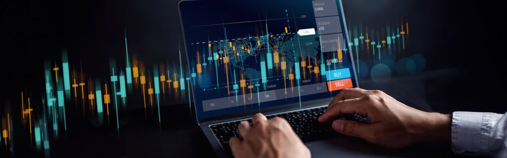 Person mit einem Laptop, auf dem eine Finanzhandelsschnittstelle mit Schwerpunkt auf Future Trading angezeigt wird, mit Kauf- und Verkaufsoptionen und bunten Candlestick-Charts auf dem Bildschirm.