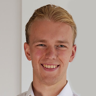 Jonas Amend mit blondem Haar lächelt in die Kamera. Er trägt ein weißes Kragenhemd vor einem schlichten Hintergrund.