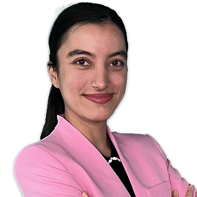 Referentin Maya Chaudhuri mit langen dunklen Haaren, die einen rosa Blazer trägt und vor einem weißen Hintergrund leicht lächelt.